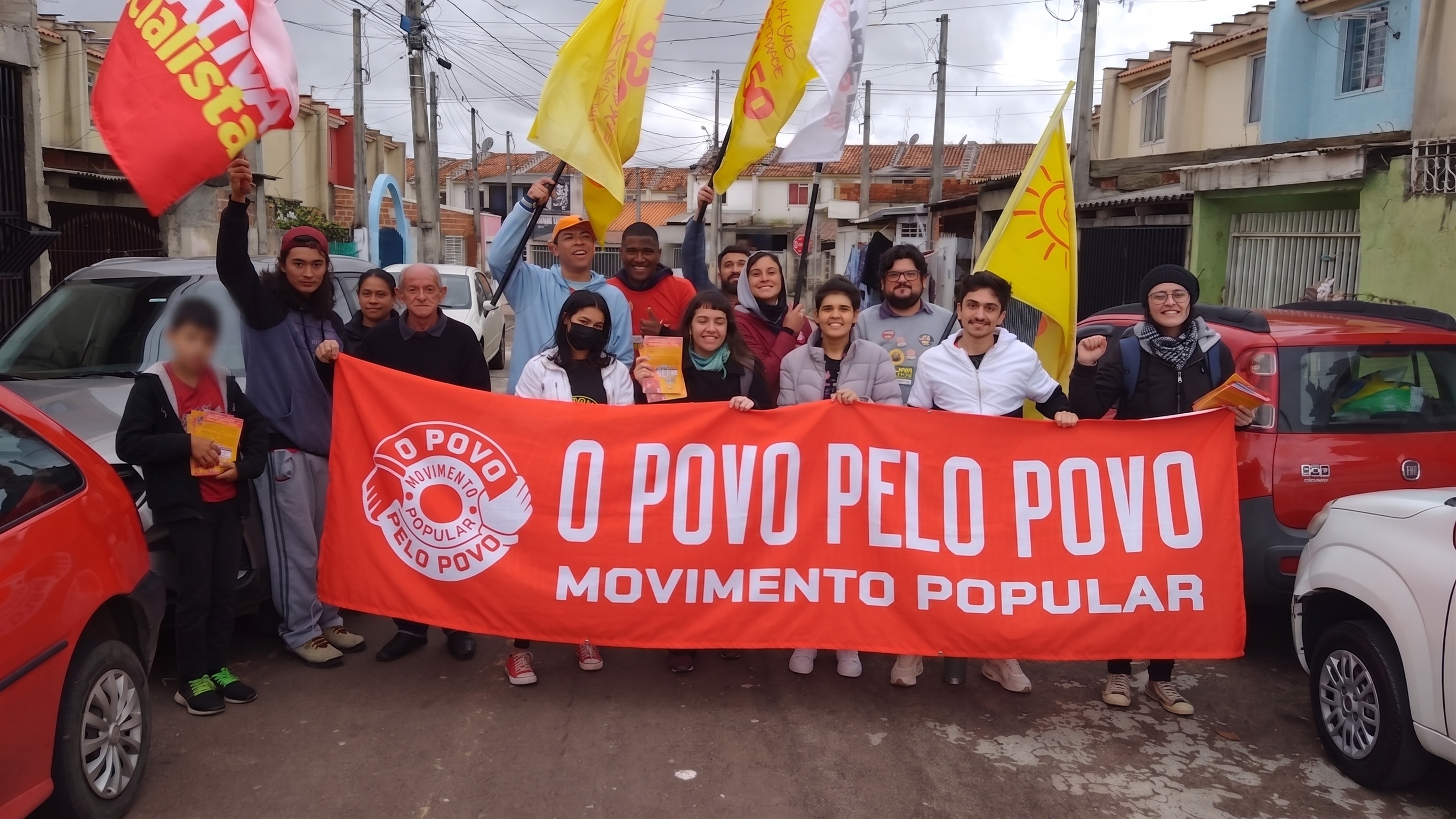 Mobilização popular em um bairro com a faixa O Povo Pelo Povo e rosto de criança protegido